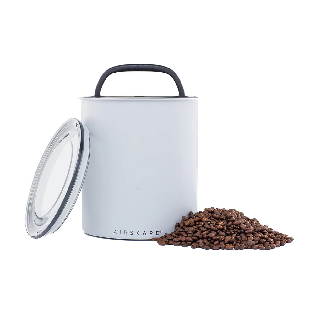 Grey coffee storage container with a handle and lid, containing coffee beans on a white background. Basic Barista Coffee Gear