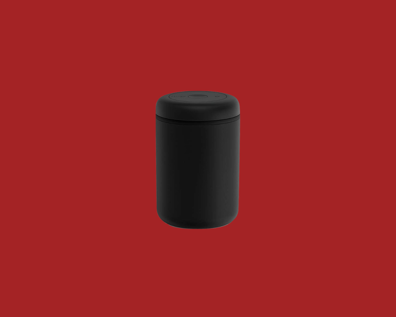 Black cylindrical Fellow Atmos Coffee Bean Storage container with lid on a red background