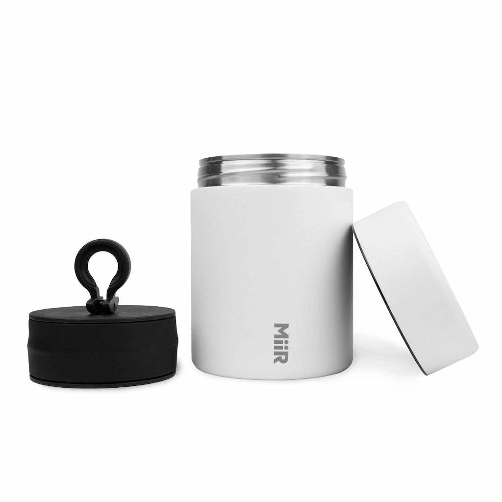 White insulated coffee bean storage jar with black lid and silver accents on a white background